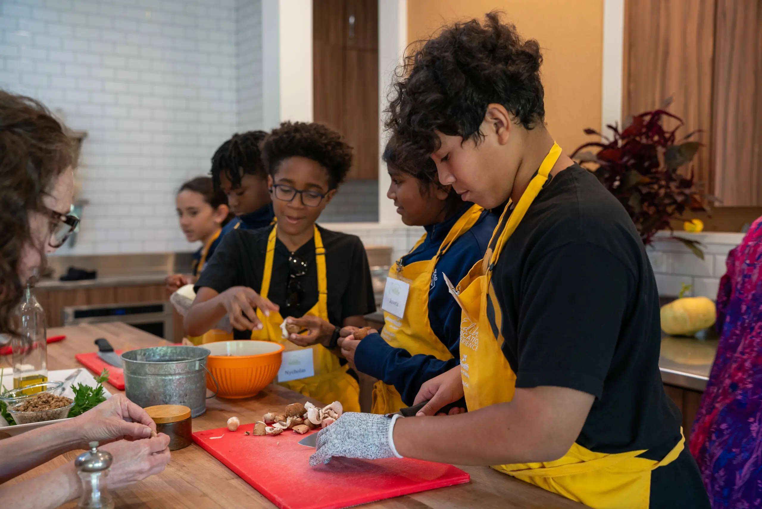 OJA students in yellow aprons cooking in the Kitchen House kitchen classroom, College Park Orlando